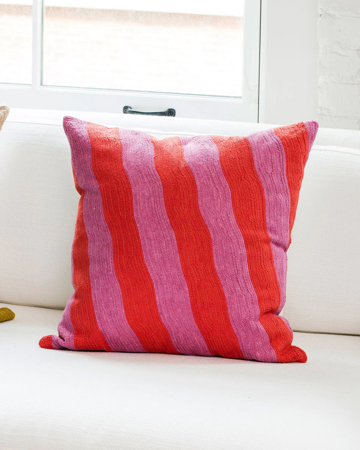coussin décoratif dusendusen rayé rose et rouge posé sur un canapé blanc
