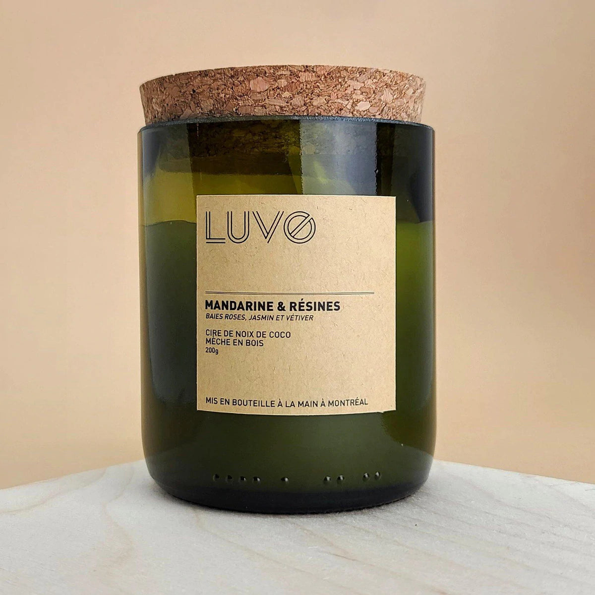 bougie Luvo parfumée mandarine et résine. Bougie dans un bocal de bouteille de vin et bouchon en liège sur fond beige