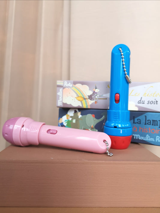 Lampe à histoires, une lampe torche rose et une lampe torche bleu et rouge posées sur un meuble