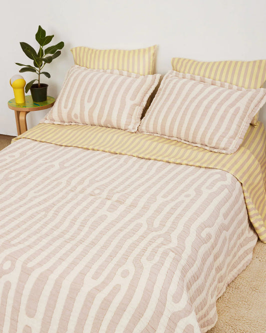 grand lit deux place avec parure de lit rayée dusendusen blanche et jaune avec quatre coussins blancs et jaunes