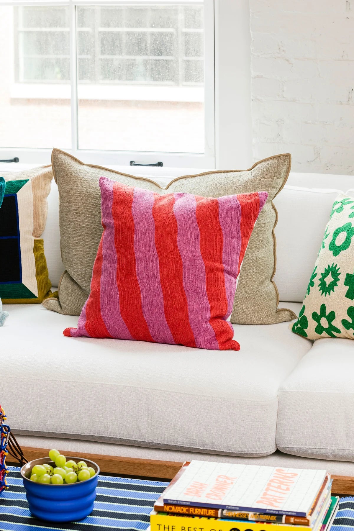 coussin décoratif dusendusen rayé rose et rouge sur un canapé blanc dans un salon